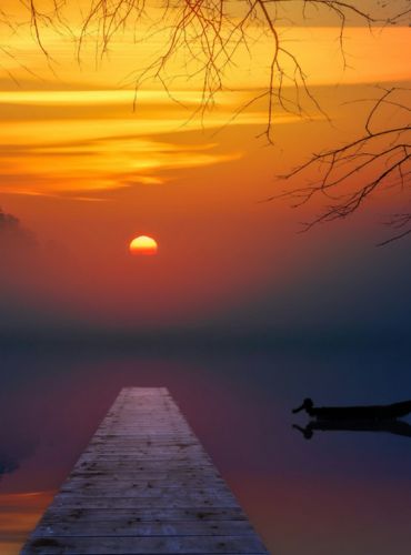 Seelandschaft mit Steg und Boot in Morgenröte