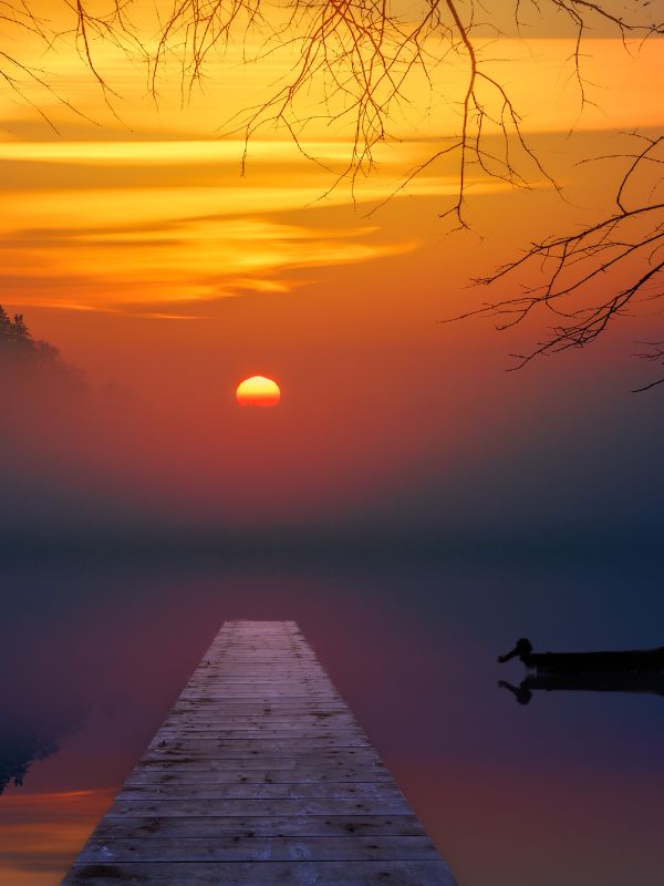 Seelandschaft mit Steg und Boot in Morgenröte